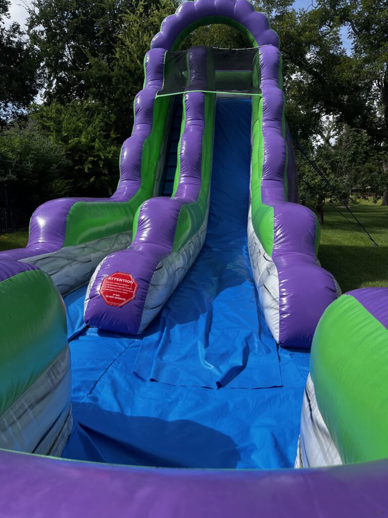 Children safely enjoying a water slide at an end-of-summer party in Sienna, Texas